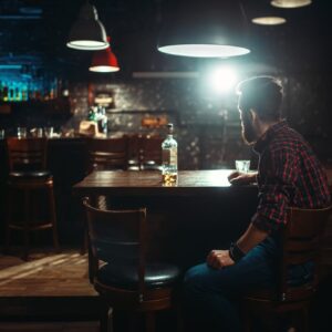 バーのカウンターに座りながらウィスキを飲んでいる男性