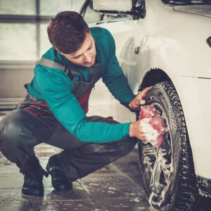 洗車場で車の合金リムを洗う男性作業員・洗車会社