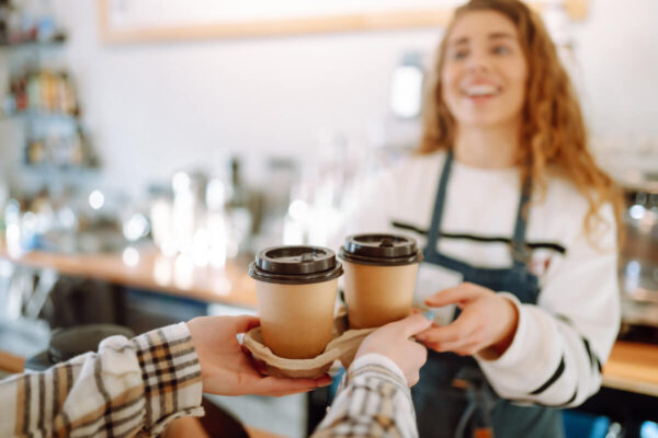 カフェで店員がお客様にお持ち帰りのコーヒーを渡している